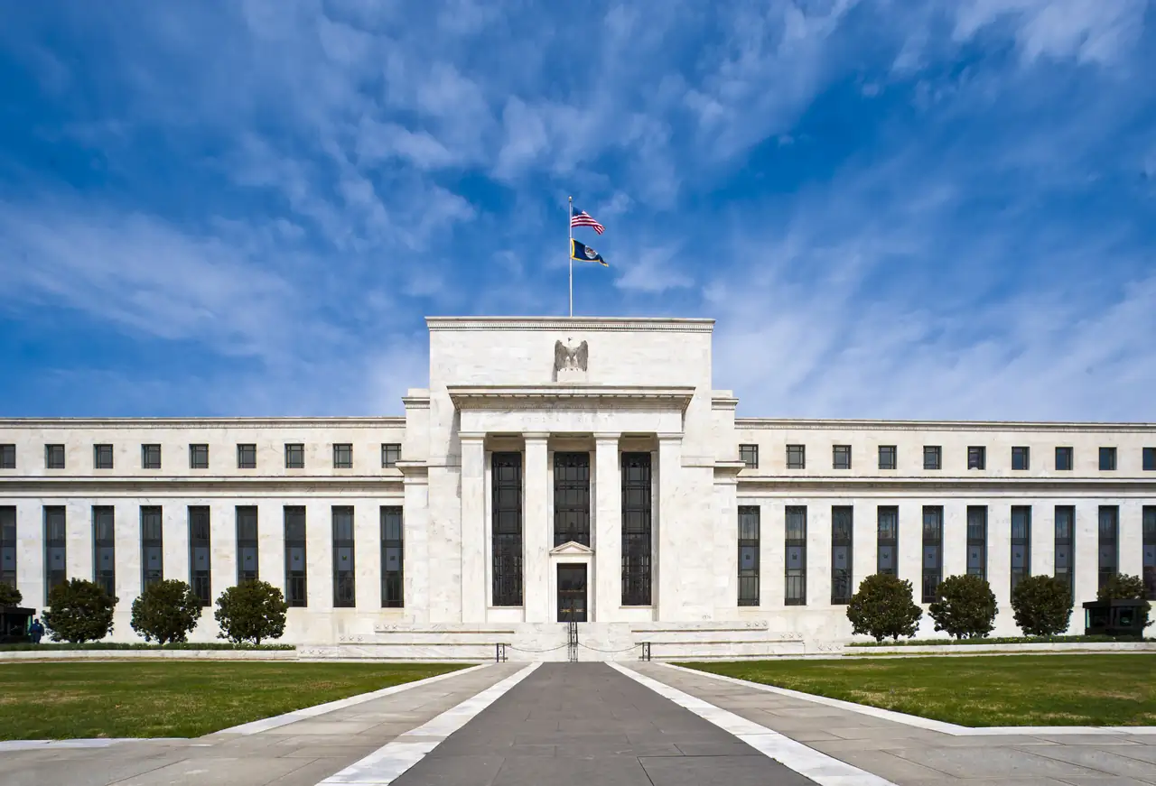 The Marriner S. Eccles Federal Reserve Board Building, a pale stone building seen from across a lawn